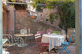 Bunte Gartenstühle und Tische im mediterranen Innenhof