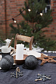 Black Christmas decorations and candle on table outside brick house