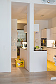 Offener Küchenbereich mit weißen Küchenmöbeln und poppig gelbem Küchenboden