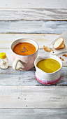 Two healthy cups of soup: tomato soup and pumpkin soup