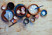 An arrangement of various bowls, flour, eggs and egg shells