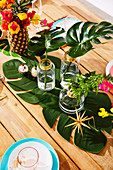 Blumenstrauß in Ananas-Vase und Blätter in Glasvasen auf weihnachtlich dekoriertem Tisch
