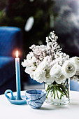 Blaue Kerze, Schälchen und weißer Blumenstrauß auf Coffeetable