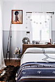 Doppelbett vor Fenster, gerahmtes Foto und Angelrute im Schlafzimmer, Klappstuhl mit verpackten Geschenken