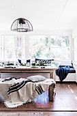 Weihnachtlich gedeckter Esstisch, passende Sitzbank mit Decke und Kissen und eingebaute Sitzbank vor Fenster