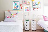 Children's room with two beds, bedside tables and children's drawings on the wall