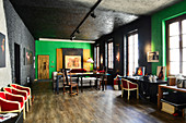 Red chairs, dining table and desk in renovated loft apartment with black and green walls
