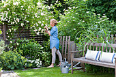 Frau riecht an weißen Rosen im idyllischen Sommergarten