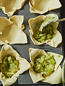 Mini quiches in a muffin tin being filled
