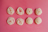 Shirataki noodle nests on a pink surface (seen from above)