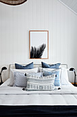 Blue bedspread on double bed with white wood-clad walls