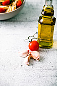 Italienische Küche: Knoblauch, Tomate und Olivenöl, im Hintergrund Pasta