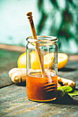 Ingredients for making immunity boosting natural drink: Lemons, mint, ginger, honey on wooden table over blue wall background