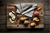 Pears sliced and whole with blueberries and peaches on a wooden chopping board