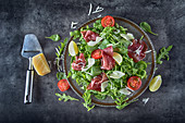 Salatplatte mit Bresaola, Rucola, Babyspinat, Tomaten, Limetten und Parmesan