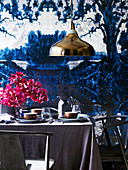 Gedeckter Tisch mit grauer Leinentischdecke und violettem Orchideenstrauss