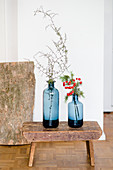 Zwei blaue Vasen mit Zweigen auf einem alten Schemel