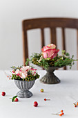 Small flower arrangements in grey metal bowls on table