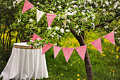 Blühender Kirschbaum mit Wimpelkett, im Hintergrund runder Tisch