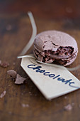 A chocolate macaron with a paper tag