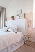 Bed with marbled headboard in bedroom in pastel shades