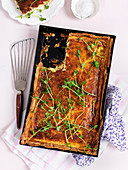 Cheese quiche in a metal baking tray sprinkled with pea sprouts (top view)