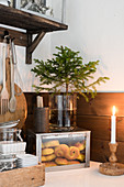 Lit candles in front of box of pastries and small Christmas tree