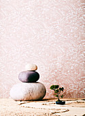 Three large stones and bonsai against a wallpapered wall