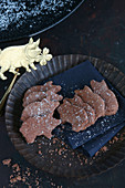 Glutenfreie Glückskekse in Schweinchenform auf schwarzem Blechteller mit goldenem Schweinchen dekoriert