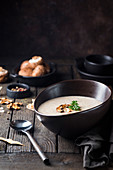 Mushroom cream soup in a bowl over dark wooden background