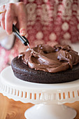 A cake being made: chocolate cream being spread onto a cake base