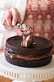 A cake being made: chocolate cream being spread onto a cake