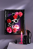3D diorama of fabric flowers and mask in black picture frame on wall