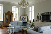Helle Hussensofas, Vitrinenschrank und Kronleuchter im Wohnzimmer