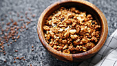 Granola in wooden bowl on gray background