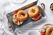 Bagels with salmon fish, cream cheese, cucumber and fresh radish slices on metallic tray