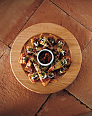 Pizzastücke und ein Schälchen Chilisauce auf Holzteller