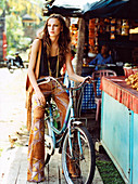 A brunette woman with a bike in front of a market stall