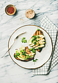 Avocado toast on plate with seasoning over marble background