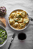 Overhead image of traditional italian ravioli with ricotta cheese and spinach tagliatelle served with a glass of wine