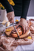 Woman slicing Braided sweet Easter bread served for breakfast with butter and jam