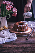 Woman drizzling lemon glaze over a bundt cake