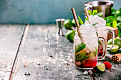 Mojito cocktail with lime, raspberry and mint in glass jars on the table