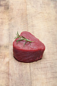 A raw fillet of beef with a rosemary sprig