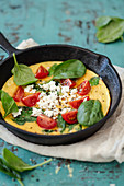Spinach frittata with tomatoes and feta in a cast iron pan