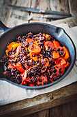 Red pepper and sausage with black rice in a cast iron pan