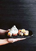 Hands holding a serving plater with tofu doughnut bites