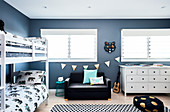 Bunk beds, couch and white chest of drawers in room with blue walls