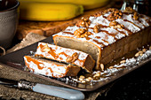 Sliced banana bread with caramel and walnuts on black background
