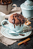 Chocolate souffle with chocolate glaze in a cup on grey background